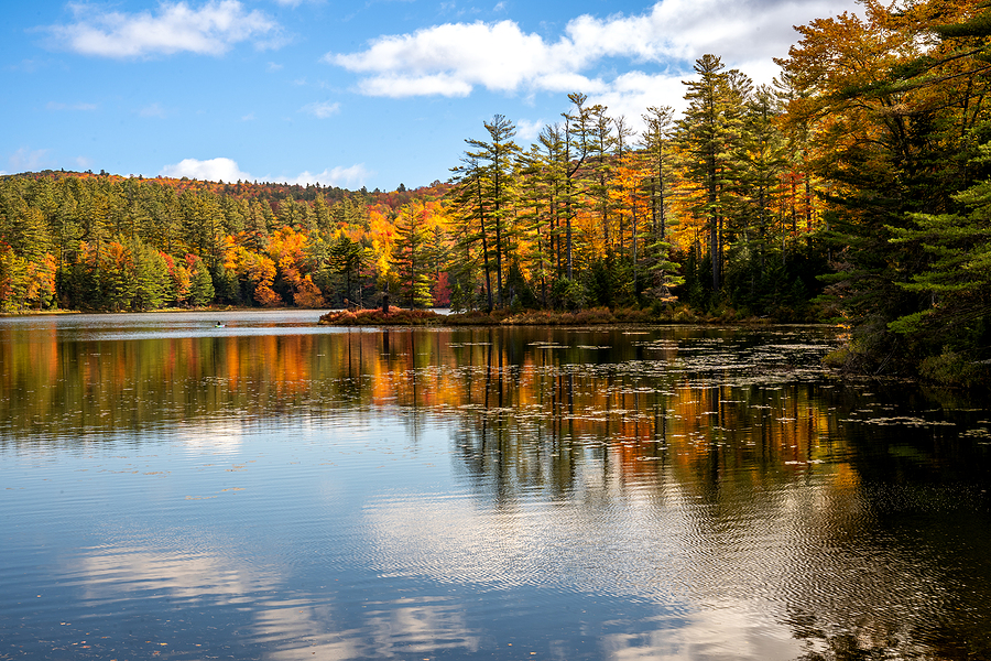 Londonderry, VT - USA - Oct. 8, 2022 Landscape autumnal view of the picturesque 102-acre Lowell Lake, located in Vermont's Lowell Lake State Park. Red, yellow orange trees reflecting in the water.