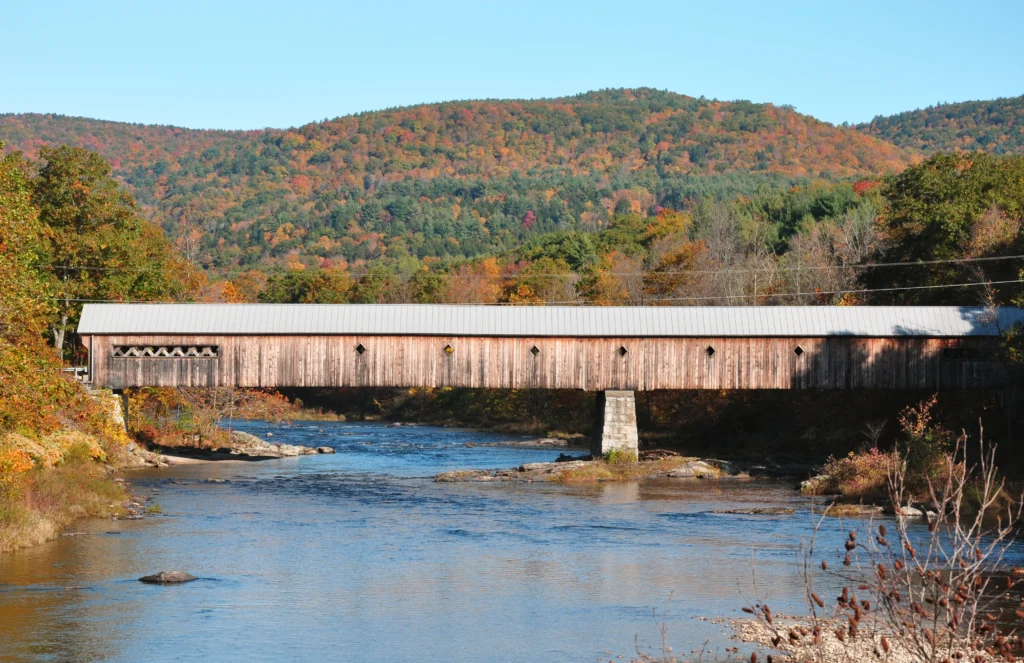 West Dummerston Covered Bridge in Dummerston, Vermont surrounded by fall foliage.